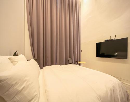 a bedroom with a white bed and a television at JS Boutique Hotel in Hwaseong