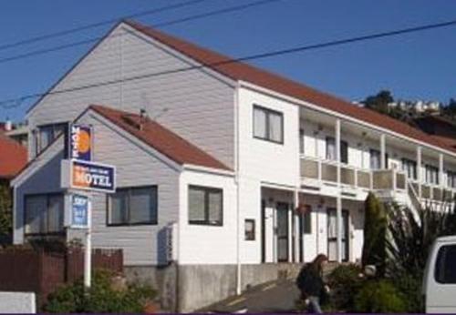 a man is walking past a white house at 88 Wallace Court Motel - Free Parking in Wellington