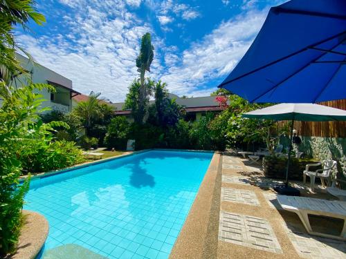a swimming pool with an umbrella and a table and chairs at TipTop Hotel, Resto and Delishop in Panglao