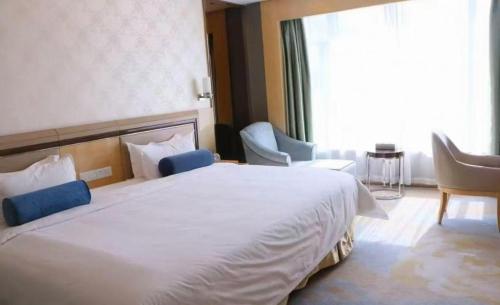 a bedroom with a large bed with chairs and a window at Shanghai Fuyue Hotel in Shanghai
