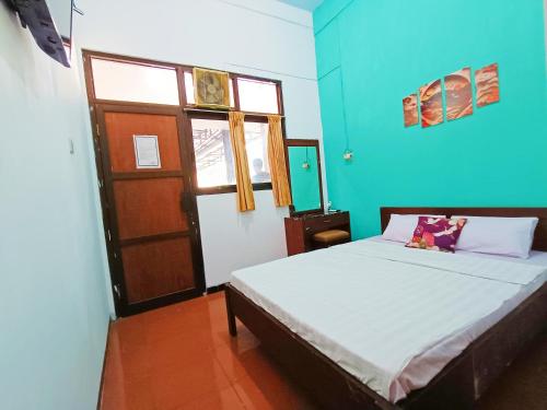 a bedroom with a bed and a blue wall at YUTAKA INN Stasiun Kota Madiun in Madiun
