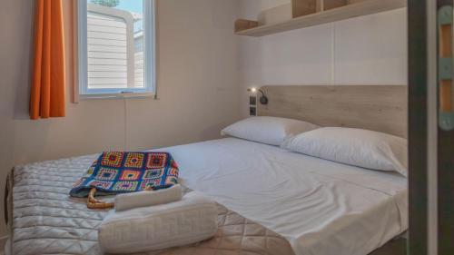 a bedroom with a large white bed with a window at Camping Grande Italia in Chioggia