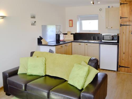ein Wohnzimmer mit einer Ledercouch in einer Küche in der Unterkunft Primrose Cottage in Winterborne Steepleton