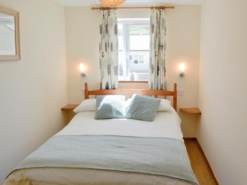 a bedroom with a large bed with two pillows at Primrose Cottage in Winterborne Steepleton