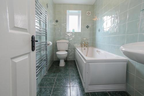 a bathroom with a tub and a toilet and a sink at Gorse Hill Farm in Newcastle