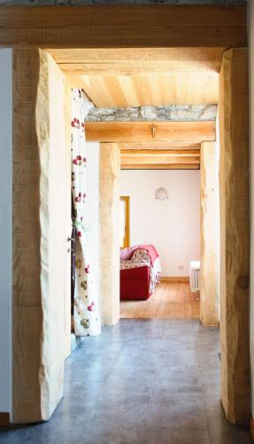 a room with a wooden ceiling and a red couch at Albergo Diffuso Dolomiti in Forni di Sotto