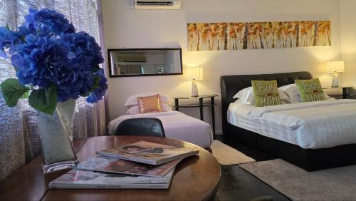 a bedroom with two beds and a table with a vase of blue flowers at KK Sunset Villa- Full Sunset Balcony, Mosquito Free, 4K TVs, 5G WIFI and more! in Kota Kinabalu