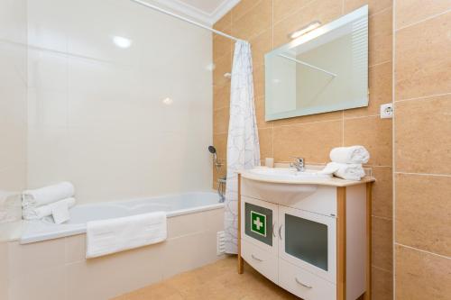 een badkamer met een wastafel en een tv op een aanrecht bij Edificio Sol Mr Sponsor Apartment in Portimão
