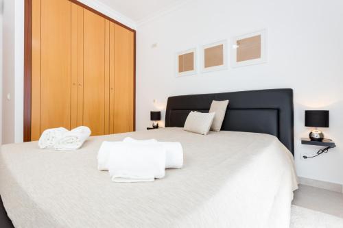 um quarto com uma grande cama branca e 2 toalhas brancas em Edificio Sol Mr Sponsor Apartment em Portimão
