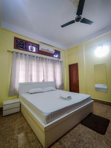 a bedroom with a large white bed with a window at Hazarika's Home in Jorhāt