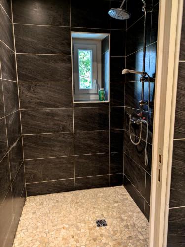 La salle de bains est pourvue d'une douche avec du carrelage noir. dans l'établissement White Chapel, à Condom