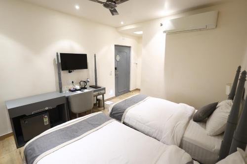 a hotel room with two beds and a television at Ananda Boutique Hotel in Kolkata