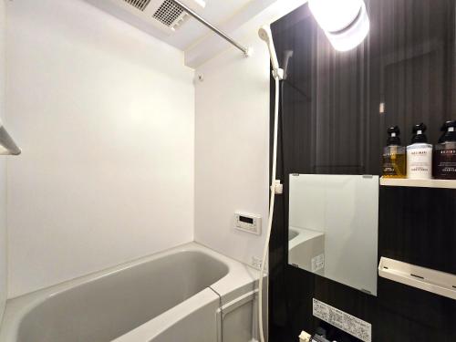 ein Bad mit einer Badewanne in einem Zimmer in der Unterkunft Comfort CUBE PHOENIX Yakuin in Susakiuramachi