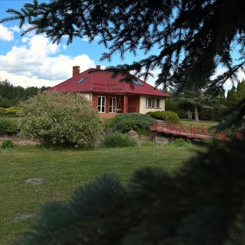 a house with a red roof in a yard at Willa u Bociana in Siemianówka