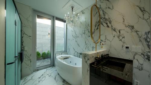 a white bathroom with a tub and a window at Eudaimonia Poolvilla Jeju 에다모니아 함덕풀빌라 in Jeju