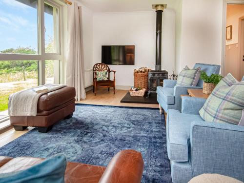 a living room with blue couches and a tv at Rowan Lodge in Resolis