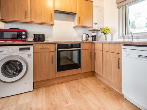 a kitchen with wooden cabinets and a washer and dryer at Rowan Lodge in Resolis