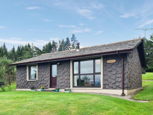 a small stone house with a large yard at Rowan Lodge in Resolis