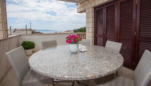 a table with chairs and a vase of flowers on a balcony at Villa Makarana Apartments in Makarska
