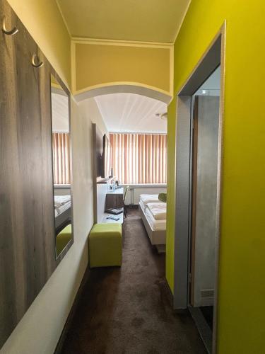 a room with yellow walls and a bed and a mirror at Hotel Am Sportpark in Duisburg