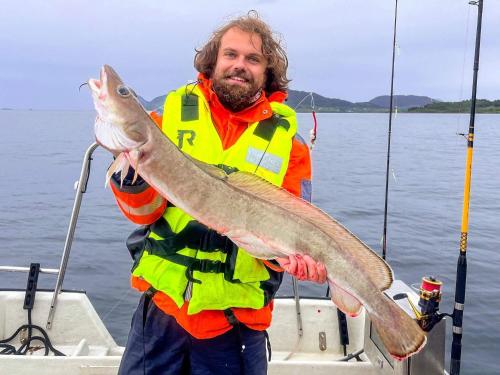 a man on a boat holding a large fish at 9 person holiday home in Åram in Sandvik