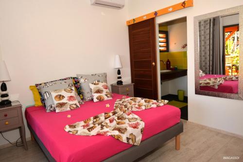 a bedroom with a bed with pink sheets and stuffed animals on it at Poz Lagon - chambre d'hôtes - Bungalow pour 2 personnes - Jacuzzi privatif - petit déjeuner - Vue sur le lagon in La Saline les Bains