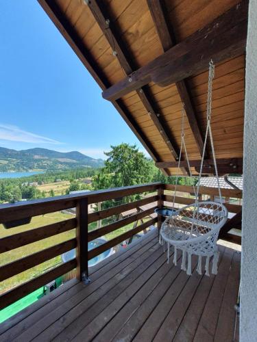 a porch with a swinging chair on a wooden deck at Cabana belvedere (VIS) in Colibiţa