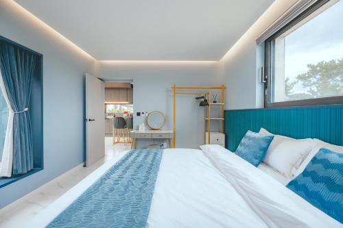 a bedroom with a large bed and a window at Eudaimonia Poolvilla Jeju 에다모니아 함덕풀빌라 in Jeju