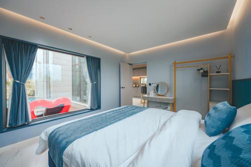 a bedroom with a large bed and a large window at Eudaimonia Poolvilla Jeju 에다모니아 함덕풀빌라 in Jeju