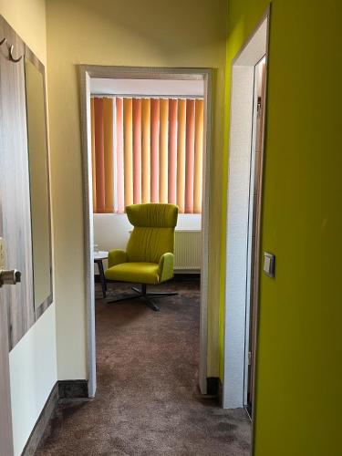a room with a green chair and a window at Hotel Am Sportpark in Duisburg