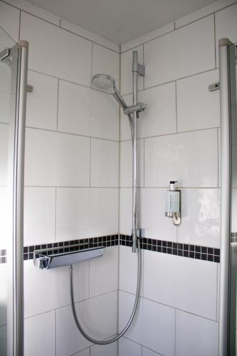 a shower in a bathroom with black and white tiles at Hotel Am Sportpark in Duisburg