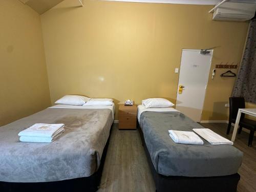 a room with two beds and a table with a chair at Central Private Hotel in Sydney