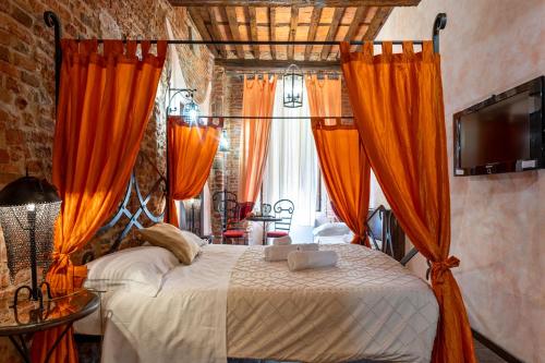 a bedroom with a bed with orange curtains at Antica Corte dei Principi Charming Rooms in Lucca