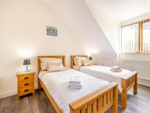 a bedroom with two beds and a nightstand and a window at Derwen Haidd in Llanafan