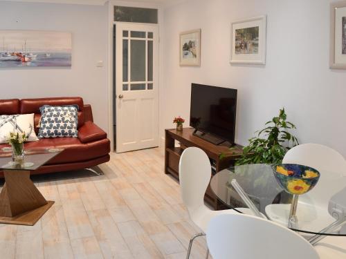 a living room with a couch a table and a television at Roland Cottage in Falmouth