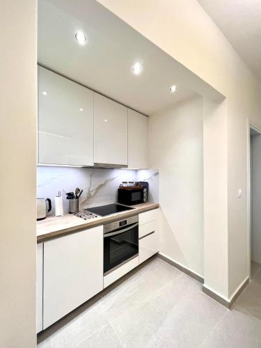 a kitchen with white cabinets and a stove top oven at KK Athens Fine Stay-Steps to Metro-Modern & Cozy Apartments in Athens