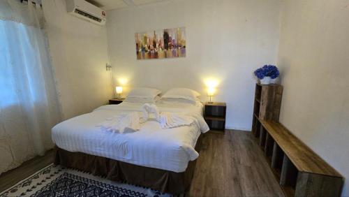 a bedroom with a bed with white sheets and pillows at KK Sunset Villa- Full Sunset Balcony, Mosquito Free, 4K TVs, 5G WIFI and more! in Kota Kinabalu