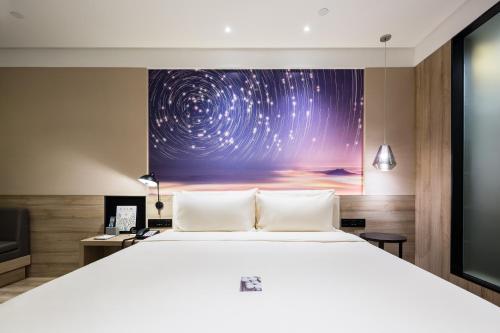 a bedroom with a large bed and a painting on the wall at Atour Hotel Qingdao May Fourth Square Yunxiao Road in Qingdao