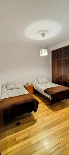 two beds in a room with wooden floors at Apartamento céntrico Quintocielo2025 in Cedeira