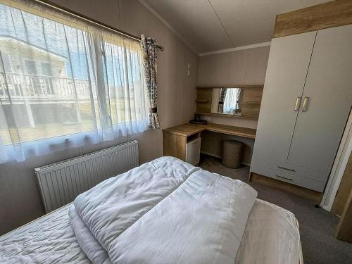 a bedroom with a bed and a desk and a window at Modern Caravan With Decking At Valley Farm, Essex Ref 46112V in Great Clacton