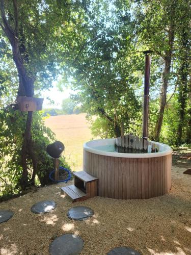 a hot tub in the middle of a yard with trees at le cocon d'amour " le fournil avec bain nordique privé " in La Chapelle-du-Fest