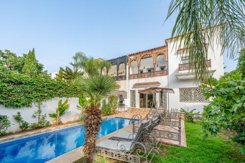 a house with a swimming pool and a palm tree at Villa 33 haut standing Avec piscine et Hammam in Tangier