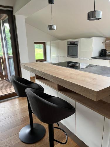 a kitchen with a counter and two black chairs at Apartment Eichhof in Innsbruck