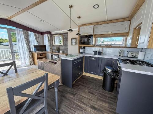 a kitchen and dining room with a table and a stove at Modern Caravan With Decking At Valley Farm, Essex Ref 46112V in Great Clacton