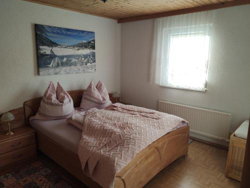 a bedroom with a bed with pink pillows and a window at Wiedehopf in Rattendorf