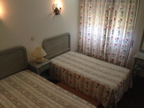 a bedroom with two beds and a lamp and curtains at Soltejo in Vila Nova da Barquinha
