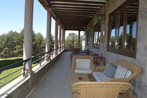 a porch with wicker chairs and tables and windows at Parador de Gredos in Navarredonda de Gredos