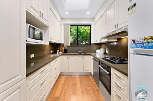 a kitchen with white cabinets and a stove top oven at Charming 3-Bedroom House in Beacon Hill in Oxford Falls