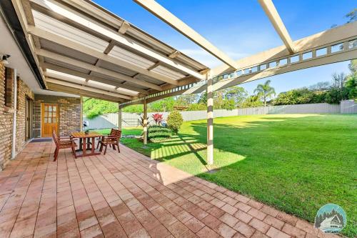 a patio with a table and chairs under a pergola at Charming 3-Bedroom House in Beacon Hill in Oxford Falls