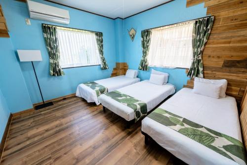 two beds in a room with blue walls and wooden floors at ハレマヤ 一軒家 Haremaya in Ishigaki Island